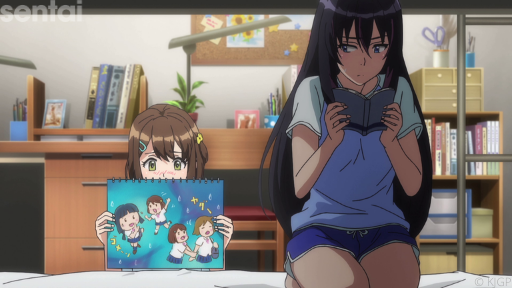 Misa from Kandagawa Jet Girls kneels on her bed while holding an open book. She looks warily over her shoulder at Rin, who is holding a sketchbook that displays a hand-drawn picture of Rin and Misa being BFFs (much to Misa's chagrin).